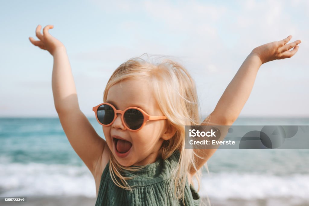 Funny kid girl playing outdoor surprised emotional child in sunglasses 3 years old baby raised hands family vacations Child Stock Photo