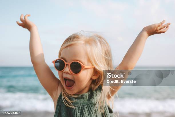 Funny Kid Girl Playing Outdoor Surprised Emotional Child In Sunglasses 3 Years Old Baby Raised Hands Family Vacations Stock Photo - Download Image Now