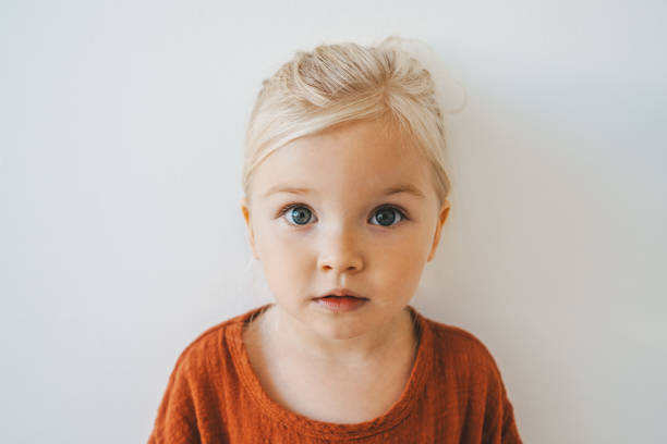 child girl cute blonde hair baby at home toddler looking at camera portrait 3 years old kid family lifestyle - meisjes stockfoto's en -beelden