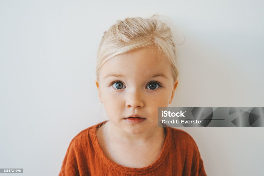 Child girl cute blonde hair baby at home toddler looking at camera portrait 3 years old kid family lifestyle Child Stock Photo