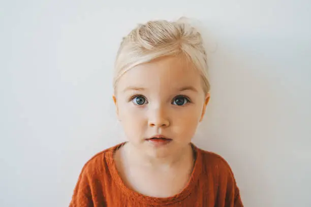 Photo of Child girl cute blonde hair baby at home toddler looking at camera portrait 3 years old kid family lifestyle