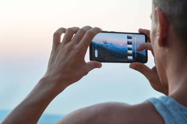 istock Young hipster man makes a photo Mountains at sunset 1355725877