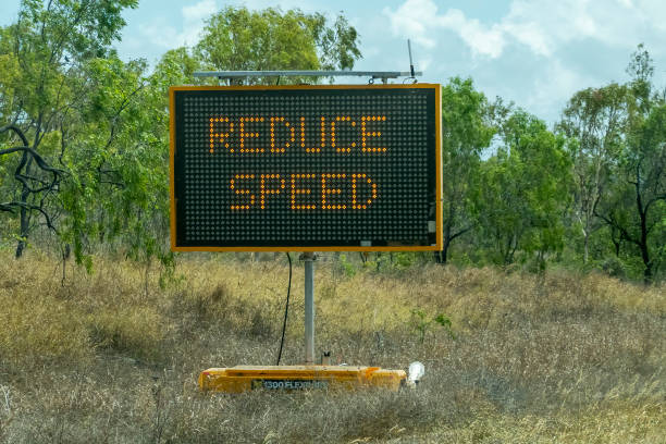 Road Speed Sign Bruce Highway Townsville to Mackay, Queensland, Australia - November 2021: Roadsign flashing lights to reduce speed during roadworks speed limit sign stock pictures, royalty-free photos & images