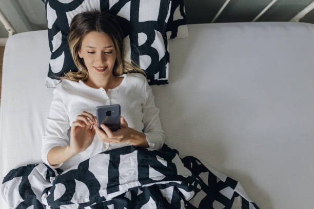istock High angle view on a young woman waking up and using smartphone in bed 1355731694