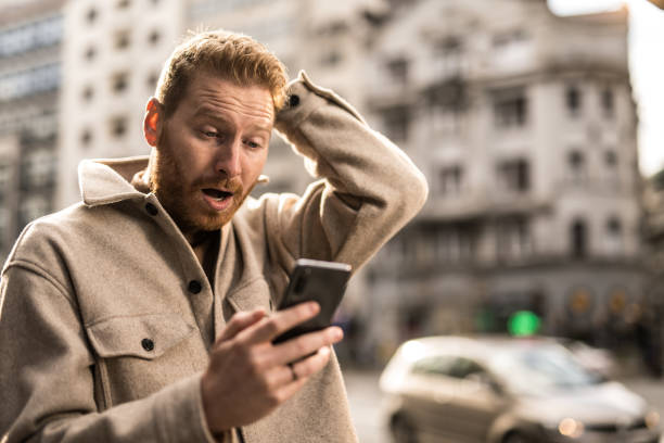 istock Shocked man using phone on city street. 1355732907