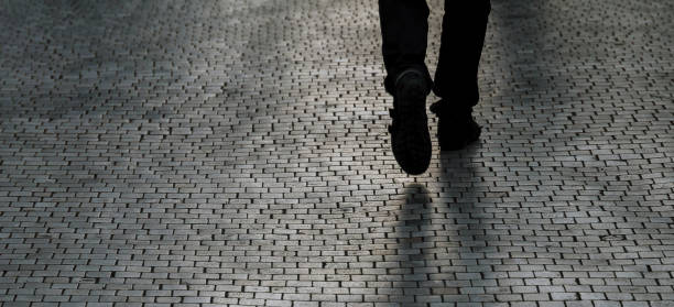 istock Silhouette or shadow of a man walking down the street one evening. 1355733372