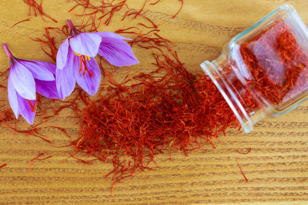 istock Saffron stigmas scattered on a wooden surface from a glass bottle. Saffron crocus flowers. 1355733415