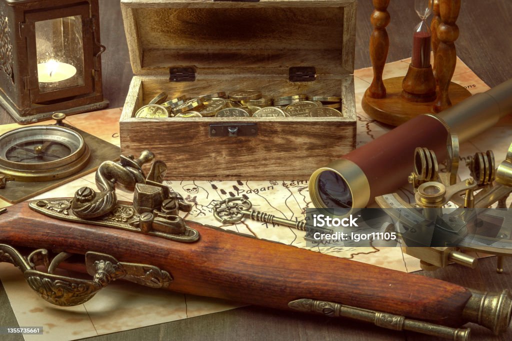 table in the pirate captain's cabin a compass, a sextant, a spyglass, an antique pistol, and a chest of gold on a table in the captain's cabin of a pirate ship. Still-life Pirate - Criminal Stock Photo