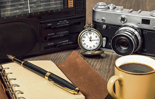 elements of journalistic paraphernalia a Cup of coffee, a camera, a radio, and a writing pad with a pen