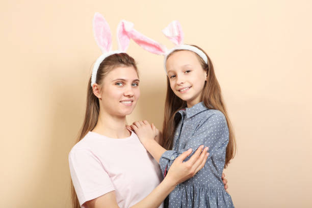 istock Mom and daughter with rabbit ears on a colored background. 1355741093