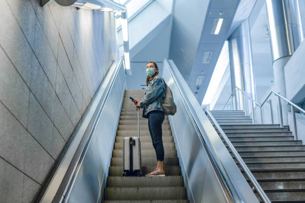 istock Young woman with suitcase using escalator in subway station 1355742027