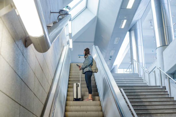 istock Young woman with suitcase using escalator in subway station 1355742029