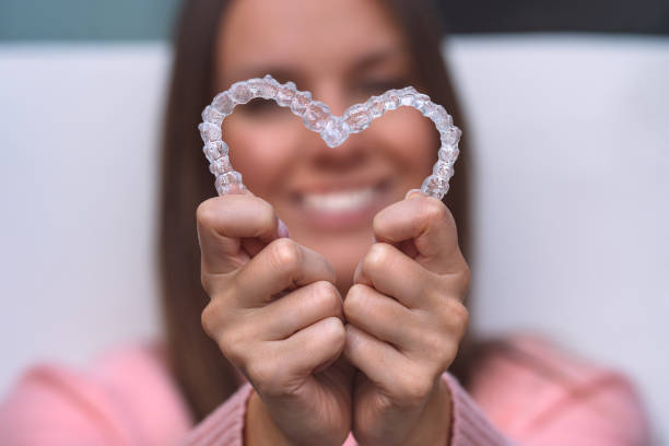 Woman with perfect smile after invisible invisalign aligners treatment Woman with perfect smile after invisible invisalign aligners treatment. High quality photo orthodontist stock pictures, royalty-free photos & images