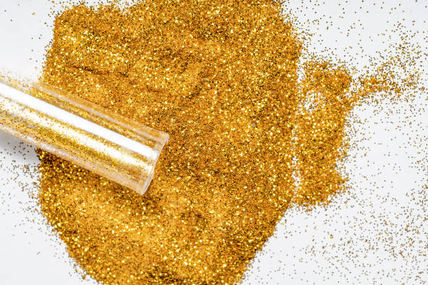 istock Gold glitter spilling out onto white surface. 1355747727