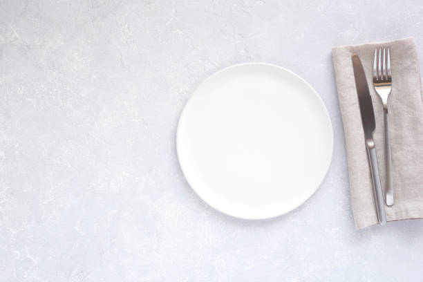 istock White plate with silver cutlery on grey 1355748511