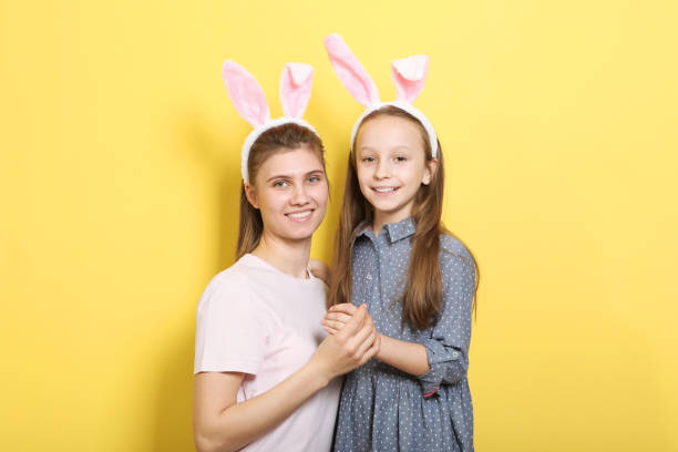 istock Mom and daughter with rabbit ears on a colored background. 1355756824