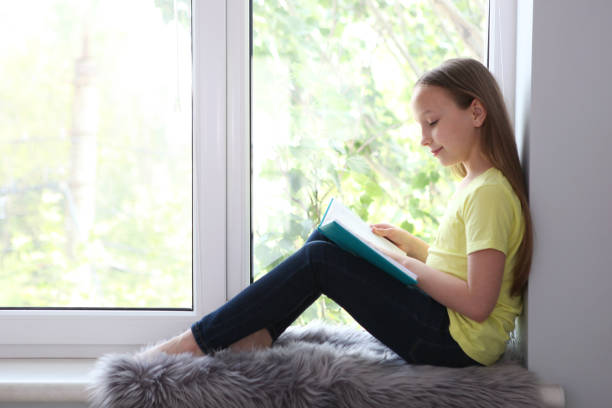 istock little girl reads a book at home. 1355761817