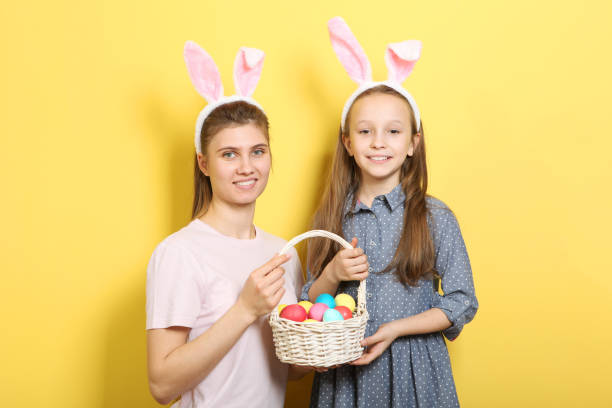 istock Mom and daughter with rabbit ears on a colored background. 1355763451