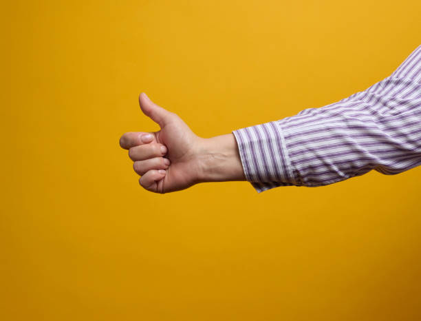 istock female hand shows like gesture on yellow background. Approval concept 1355763623
