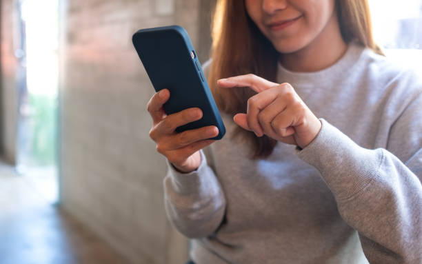 istock a young woman holding and using mobile phone 1355769627