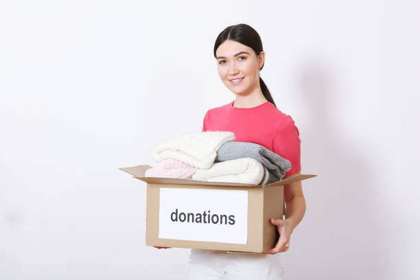 istock Girl with a box of donations on a colored background. place for text. 1355770320