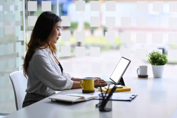 istock Side view beautiful businesswoman working with computer tablet in modern workplace. 1355771375