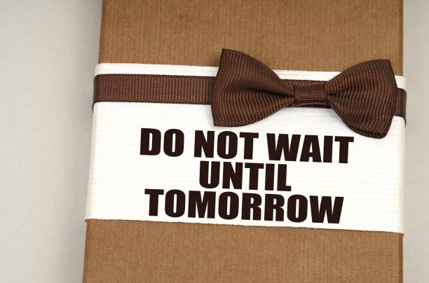 istock On the packing box with a bow-tie the inscription - Do Not Wait Until Tomorrow 1355775624
