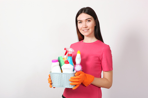 A young housewife holds in his hands cleaning products on a colored background. High quality photo
