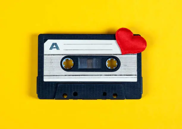 Old Audio Cassette with a Red Heart on the Yellow Paper Background closeup