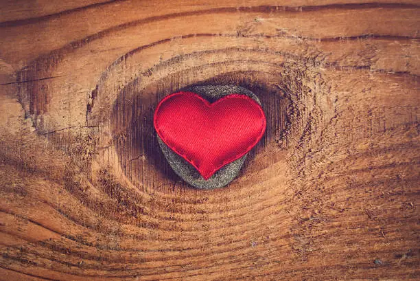 Red Heart Shape on a Pebble and Wooden Planks Background closeup
