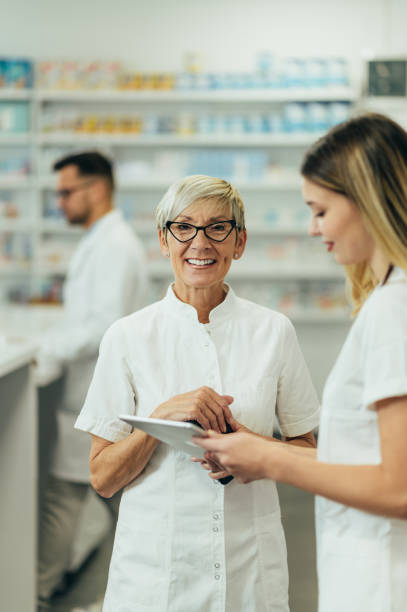 istock Senior female pharmacist using a tablet while working in a pharmacy with her young colleague 1355785674