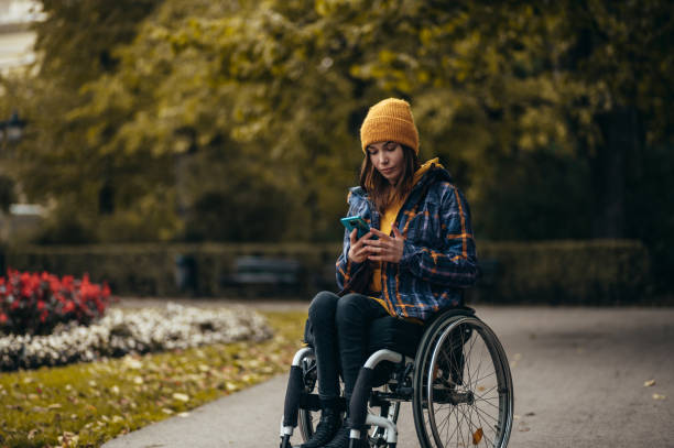 istock Woman with disability using a smartphone while out in the city park 1355785713