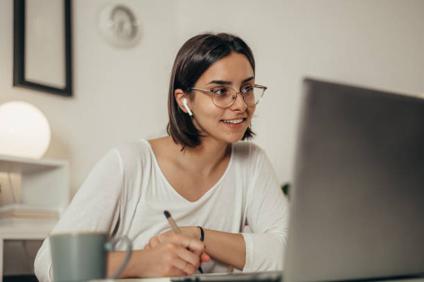 istock Woman writing in a notebook and using a laptop while working from home 1355785715