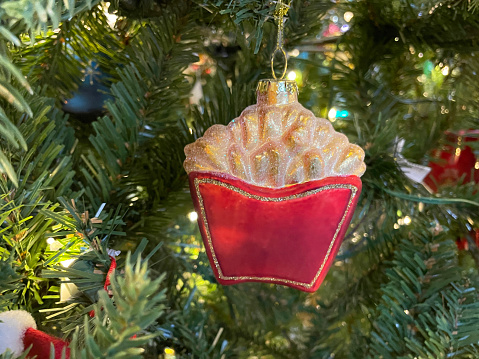 Stock photo showing a close-up view of an artificial, spruce Christmas tree with food themed decorations with white fairy lights.