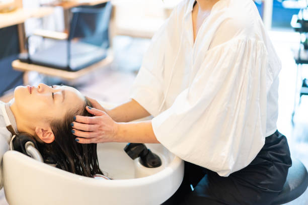 friseur shampoonieren der haare am shampoo-tisch - bathtub asian ethnicity women female stock-fotos und bilder