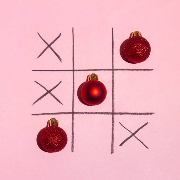Red Christmas decoration tic tac toe game on pink background. New year minimal creative idea. Flat lay holiday concept