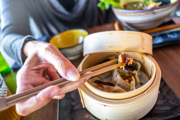 A woman eats Asian food with chopsticks