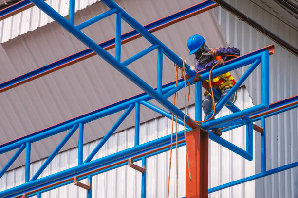istock construction worker with safety equipment is welding metal roof warehouse building structure in construction site 1355795302