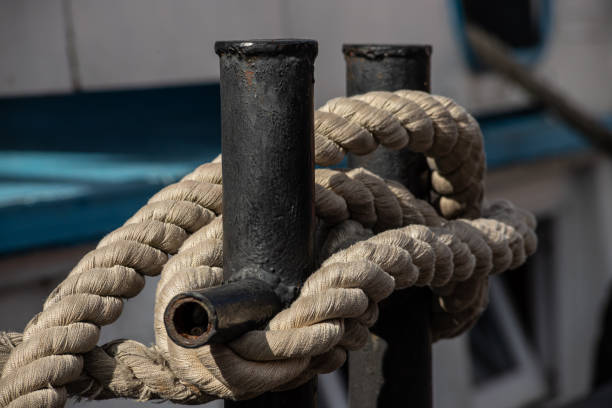 istock Worn old rusty mooring bollard with heavy ropes on the deck of a ship, closeup 1355796624