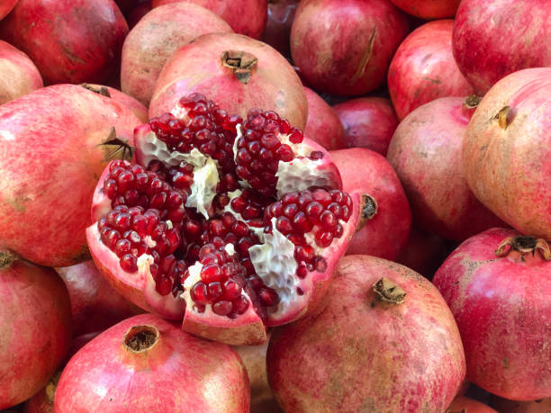 istock background with whole and one cut pomegranate fruit with ripe red seeds 1355801847