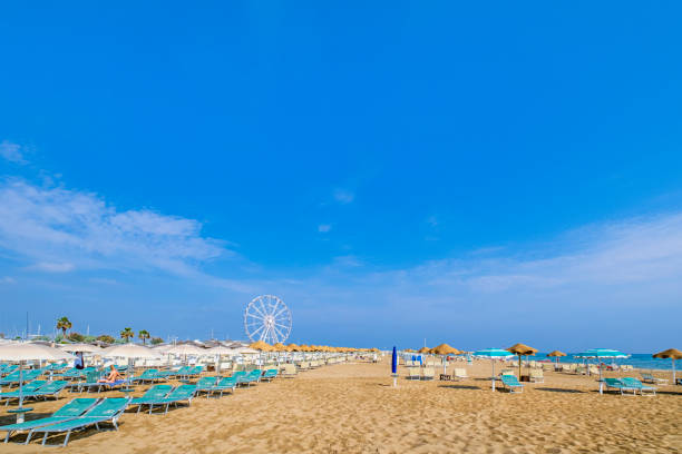 People relaxing on the beach of Rimini. Ferris wheel in background.