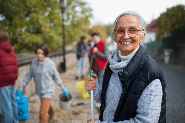 femme bénévole senior avec l’équipe de nettoyage de la rue, concept de service communautaire - dépollution photos et images de collection