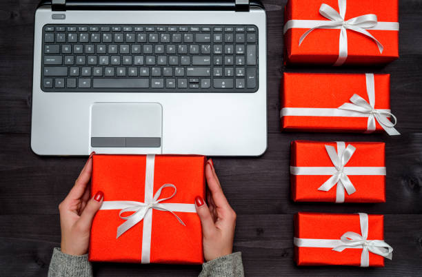 istock Top view of open laptop computer, red gift boxes on wooden table, copy space. Flat lay. Online shopping, sales. Woman holding present in hands. Valentines day, March 8 (Women's Day), Mother's day 1355805126