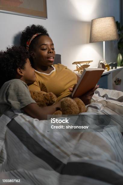 Careful Blackwoman Reading Fairy Tale To Son Stock Photo - Download Image Now - Reading, Family, Relaxation