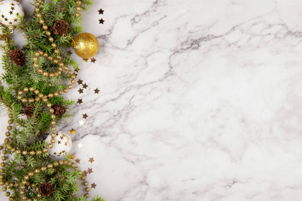 istock Christmas greeting card or frame with fir tree branches and festive decor on light grey marble background with pine cone 1355809546