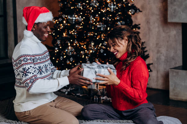 istock Black man presents girlfriend Christmas gift in festive mood 1355814665