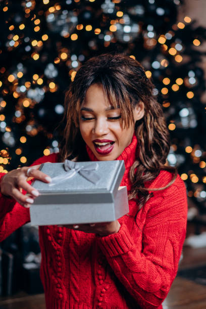 istock Young curly woman gets surprised with Christmas present 1355814687