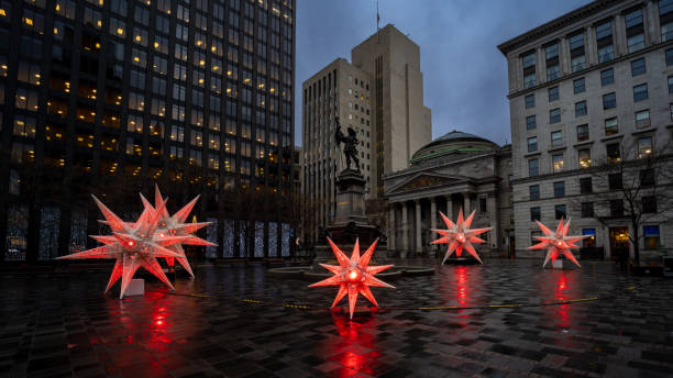 the place d'armes in Montreal, in preparation for the month of December with illuminated Christmas decorations surranding the statue of Maisonneuve the Place d'Armes in Montreal, in preparation for the month of December with Christmas decorations, Notre Dame Basilica in the background, The Monument à Maisonneuve is a work by Louis-Philippe Hébert in memory of Maisonneuve, founder of Montreal, installed in 1895 in the center of Place d'Armes in Old Montreal. place darmes montreal stock pictures, royalty-free photos & images