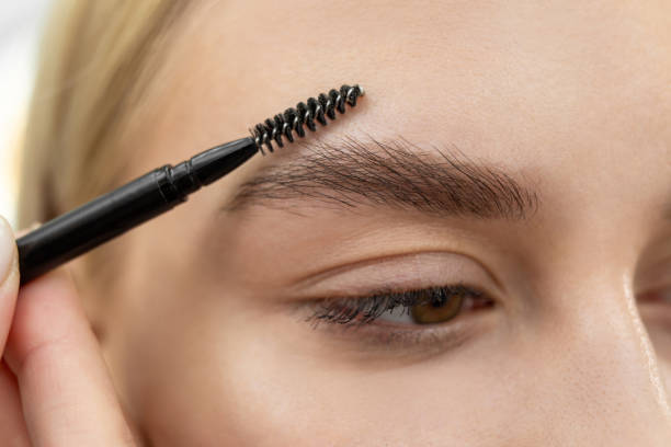 istock Closeup beautiful woman with eyebrow brush tool, makeup artist combs eyebrows close up. 1355816918