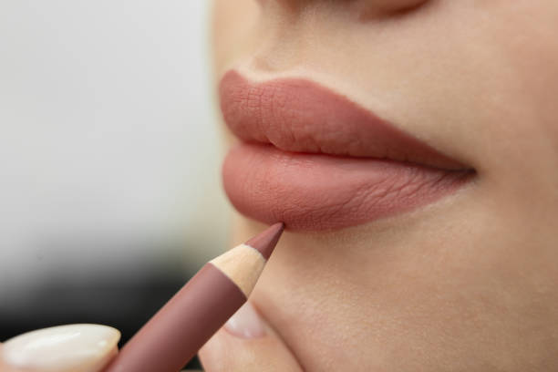 maquillaje de labios. primer plano de una cosmetóloga pintándose los labios con un lápiz antes del maquillaje permanente - lip liner fotografías e imágenes de stock